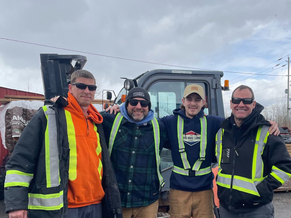 Four members of the Emard Bros. Lumber yard crew in high visibility gear