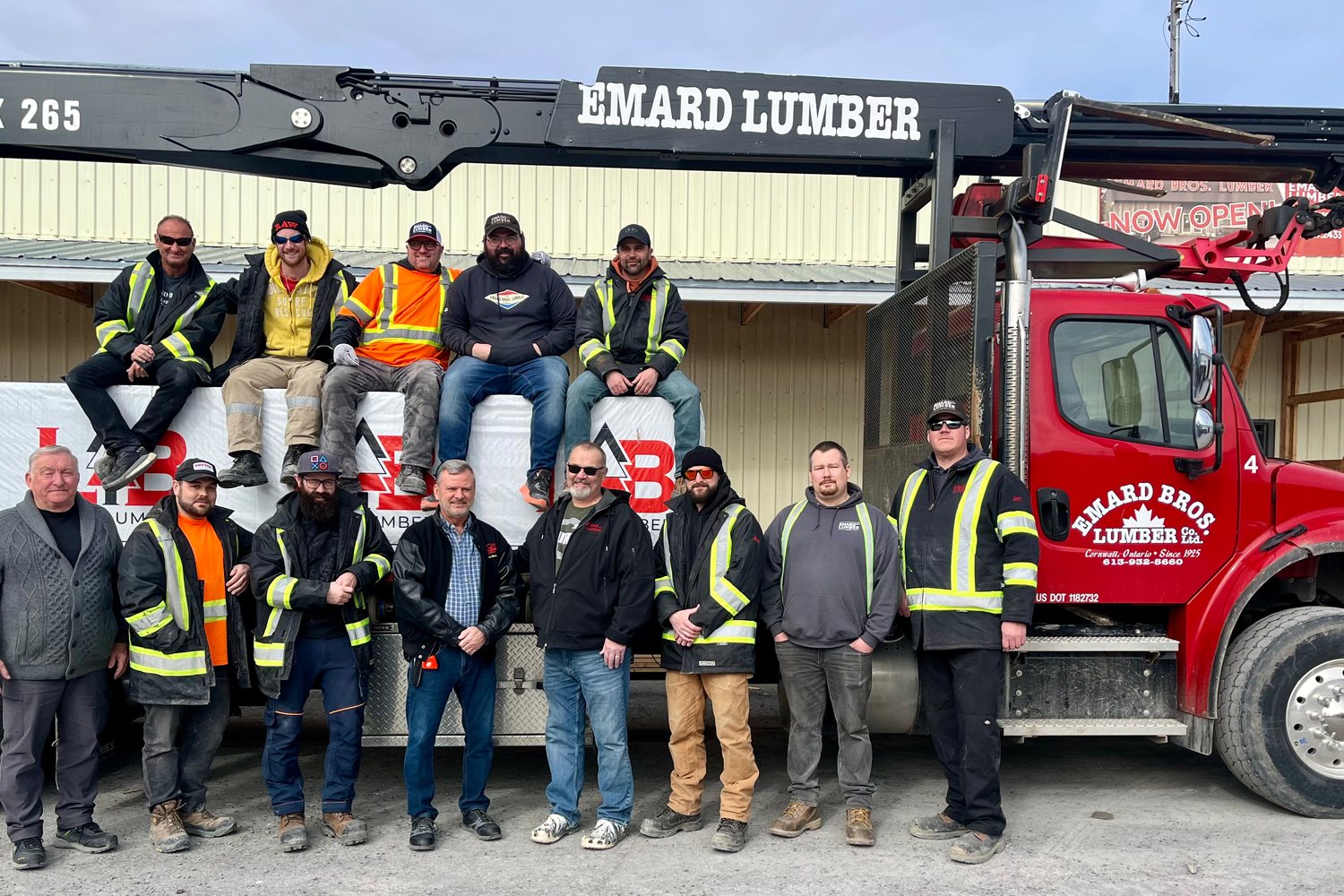 The Emard Bros. Lumber crew standing in front of a red boom truck at the Cornwall yard