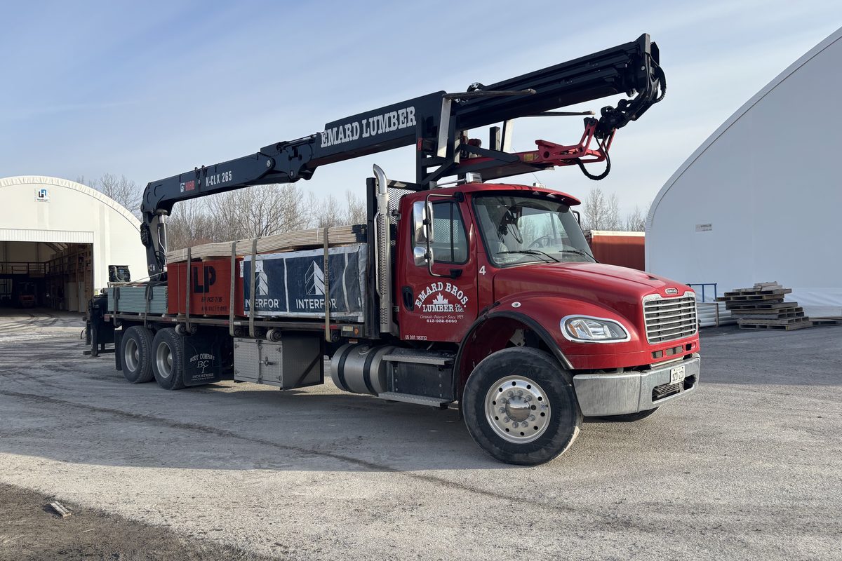 An Emard Bros. Lumber boom truck parked at the yard